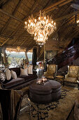Elegant antique furniture and chandelier in rustic house with thatched roof
