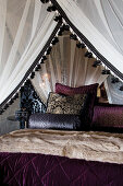 Four-poster bed with canopy and view of scatter cushions with elegant velvet covers