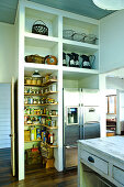 Kitchen with open-fronted shelves and integrated pantry next to fridge combination
