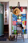 Straw hat and gardening utensils hanging on coat rack in rustic foyer
