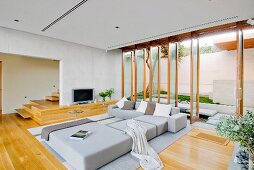 Minimalist sofa combination in front of open floor-to-ceiling windows in modern living room with parquet floor