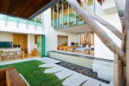 View into kitchen and living room of modern house with open, panoramic facades leading to manicured garden