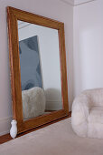 Großer, holzgerahmter Spiegel mit Reflektion eines modernen Gemäldes und Kuschelsessel in Altbauwohnzimmer