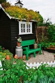 Gartenhäuschen mit Grasdach und grün lackierter Bank
