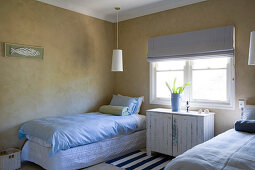 Simple bedroom with a single bed, a hanging lamp above it and chest of drawers under the window