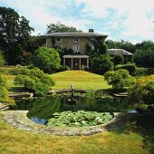 Summer atmosphere in park-style garden with pond in front of grand country house