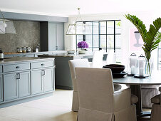 Elegant, white armchairs at dining table in traditional kitchen