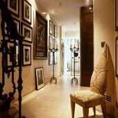 Unusual chair with brocade-patterned upholstery in elegant hallway of house with gallery of pictures and stone-flagged floor