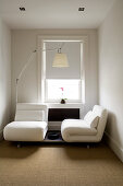 Small, elegant guest room with folding armchair elements and designer lamp by Artemide