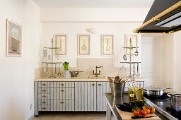 Retro country house style in French kitchen-dining room with brass shell handles on light grey striped cupboard doors