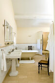 Ensuite bathroom in French country house style with retro pedestal sinks and free-standing bathtub