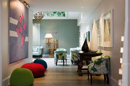 Offener Wohnraum mit farbigen Sitzsäcken vor modernem Bild an Wand und traditioneller Sitzgarnitur in Abwechslung