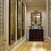 Decorative plate on antique, half-height cabinet below gilt-framed mirror in manorial hallway