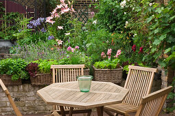 Holztisch mit Stühlen, umgeben von Pflanzen auf einer Terrasse