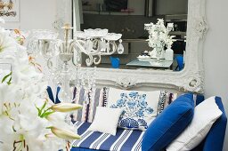 Baroque wall-mounted mirror below blue striped sofa with scatter cushions