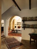 Collection of ceramic vases on shelves next to arched doorway with view into Mediterranean living room