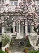 Blühender Magnolienbaum vor Villa und spielendes Kind auf Steintreppe
