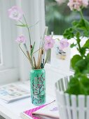 Paintbrushes in can next to potted plant on windowsill
