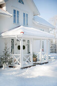 White wooden house with roofed porch in winter atmosphere