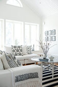 Pale, Scandinavian-style attic interior with comfortable sofa set and scatter cushions