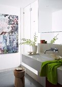Holzhocker vor modernem Waschbecken an gefliester Wand neben Duschkabine mit Glastüren
