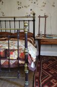 Brass-framed double bed and patterned rug in rustic setting