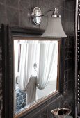 Vintage mirror with sconce lamp on tiled wall in Mediterranean bathroom