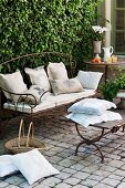 Wrought-iron garden bench with cushions on cobbled terrace seating area