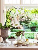 Blick in den Garten über gedecktem Tisch mit antikem Teegeschirr, handgefertigter Keramik und Orchidee