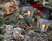 Winter arrangement with tea light holders, lanterns and pine cones