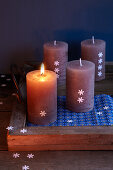 Group of candles on rustic wooden tray with Christmas decorations