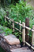 Bambus-Beet hinter Naturstein-Einfassung und mit Schnüren gebundenem Bambus-Gatter