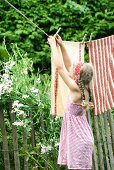 Pretty tea towels hanging on washing line as screen along garden fence