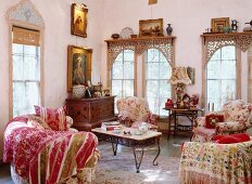 Living room with a style mix - classic, floral upholstered furniture and antique chest of drawers under baroque paintings