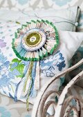 Hand-crafted cardboard rosette with decorative ribbons on cushion