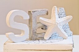 White-painted wooden letters and starfish figurine on wooden box