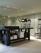 Black-painted workbench as washstand in bathroom with mirrored wall and Chiavari chair in background