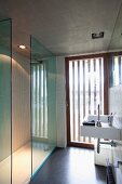 Puristisches Badezimmer mit gestreift satinierter Terrassentür und Einbaustrahlern in der Sichtbetondecke