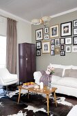 Corner of living room with white seating, old locker and framed photos on wall