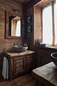 Helles, holzverkleidetes Badezimmer mit rustikalem Waschtisch und Stein-Waschschüssel; an der Wand ein quadratischer Badezimmerspiegel