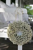 Wreath of white flowers hanging on arm of bench