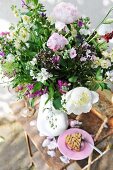 Bouquet of garden flowers in vase and slice of cake on rusty garden table