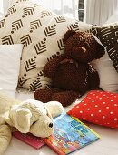 Stofftiere, Kissen und Kinderbücher auf dem Bett
