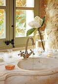 Romantic, Mediterranean bathroom - water running from retro tap fitting into curved marble basin