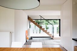 Blick über Essplatz in offenem Designer Wohnraum mit Treppe vor Glasfront beklebt mit Folienbuchstaben