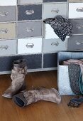 Damenstiefel auf Holzboden vor Vintage Schubladenschrank mit Kleidungsstück in offener Schublade