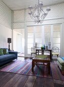 Metal chandelier above carved wooden coffee table on striped rug in foyer with white wooden latticed walls