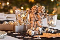 Pair of angels and Christmas decorations next to glass tea light holders