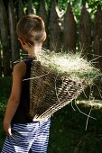 Boy carrying basket of hay in garden