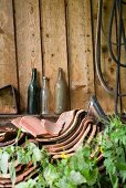 Old glass bottles, broken clay tiles stacked by wall outdoors